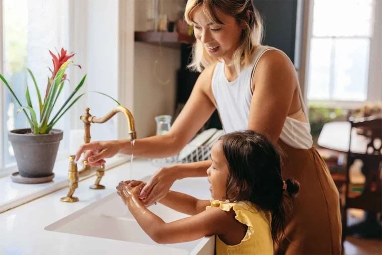 Mom helping daughter wash her hands