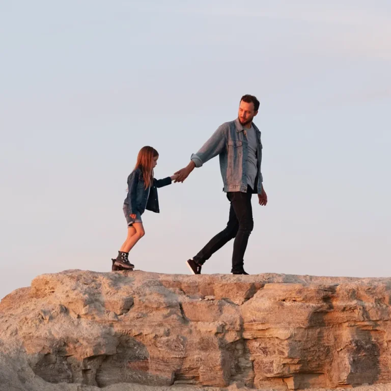 dad leading daughter across a rock formation