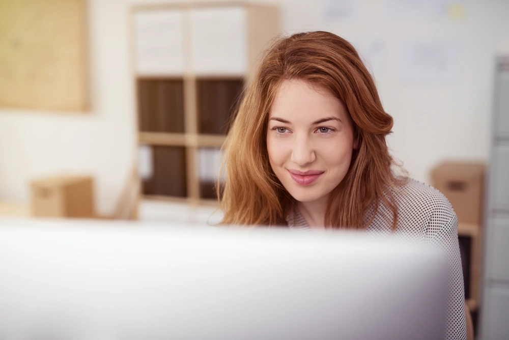 woman smiling and looking at computer screen