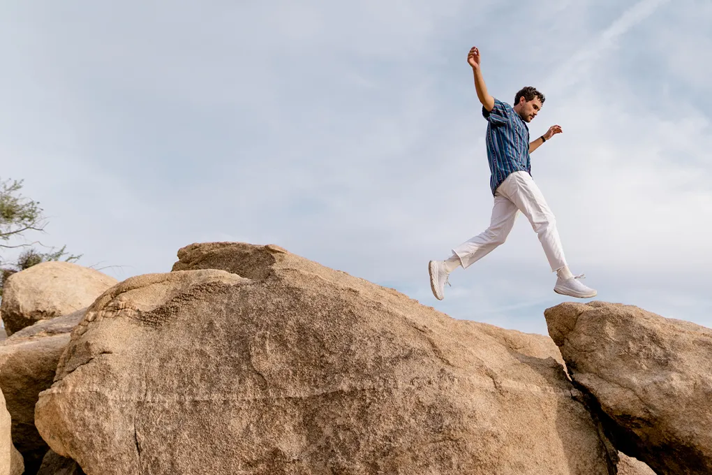 man jumping from rock to rock