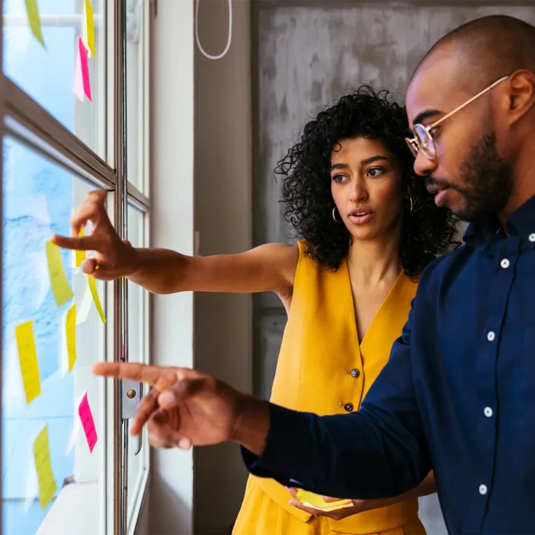 two team members brainstorming with sticky notes