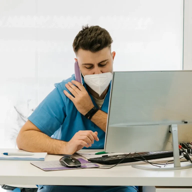 healthcare professional talking on phone while sitting in front of computer