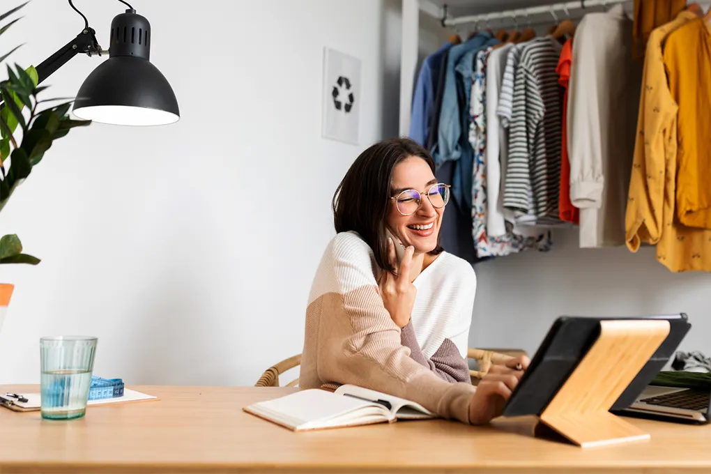 woman smiling and talking on phone while using ipad